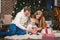 Family celebratory Christmas evening. Family three Caucasian people sitting under coniferous tree Christmas tree on floor of carpe