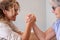 Family challenge, curly blonde daughter and senior mother joking arm wrestling on the table at home face to face