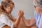 Family challenge, curly blonde daughter and senior mother joking arm wrestling on the table at home face to face