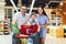 Family with child and shopping cart buying food at grocery store or supermarket