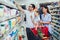 Family with child and shopping cart buying food at grocery store or supermarket