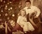 Family with children pose under Christmas tree.