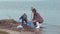 Family cleaning beaches, young female volunteers with kid boy clean polluted nature from plastic trash near water on