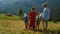 Family coming down hill enjoying summer. Couple walking with kids on nature.