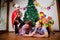 Family consisgitng mother, father and two brothers in carnival costumes at Christmas or new year near the Christmas tree in the