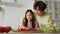 Family cooking. Young cheerful asian daddy teaching his little daughter to prepare salad, cutting vegetables together