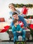 Family couple with a boy with gifts are having fun playing at home in Christmas decorations