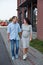 Family couple men and a young pregnant woman walking holding hands and laughing along the city windows