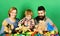 Family with curious faces hold teddy bears near construction blocks.