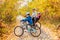 Family cycling in golden autumn park, active father and kids ride bikes, family sport and fitness