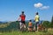 Family cyclists, mother, father and kid resting with bikes on top of grassy hill