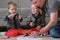 Family dad and two twin brothers draw together markers and felt pens sitting on the floor.