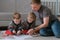 Family dad and two twin brothers draw together markers and felt pens sitting on the floor.