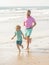 family of daddy man and child boy running on sunny beach together, travel