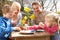 Family Decorating Easter Eggs On Table Outdoors