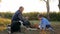 Family dinner, grandfather and child sit on blanket near basket and play with dog