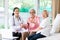 Family doctor or nurse wearing white coat and stethoscope with smiling senior patient during home visit,young female home caregive