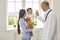 Family doctor.Senior doctor giving high five to girl at medical office. Little patient with her mommy on visit to