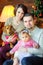 Family with dog sits and hugs near the festive Christmas tree