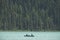 Family doing canoe in a beautiful blue lake located in the Canadian Rockies and a stunning background made of fir trees