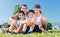 Family dressed in white in park in summer sitting in meadow