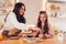 Family drinking tea with cookies at home. Mother and daughter laughing dipping biscuits in cups