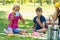 Family drinks tea at a picnic, thermoses with water are standing nearby