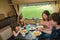 Family eating together in RV interior, parents and kids travel in motorhome camper, caravan on family vacation