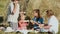 Family eats melon during picnic at the meadow