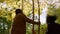 Family enjoy autumn park dancing under falling leaves in warm golden sunlight.