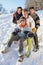 Family Enjoying Sledging Down Snowy Hill