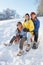 Family Enjoying Sledging Down Snowy Hill