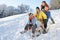 Family Enjoying Sledging Down Snowy Hill