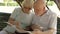 Family enjoying vacation. Seniors sitting on bench in park studying city map looking for showplaces