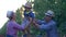 Family of farmers, happy mom and daddy with little child into hats fun spend leisure at garden in sun beam among trees