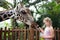 Family feeding giraffe in zoo. Children feed giraffes in tropical safari park during summer vacation. Kids watch animals. Little