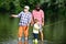 Family fishermen fishing with spinning reel. Boy with father and grandfather fly fishing outdoor over river background.