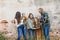 A family of five with two girls and a baby boy standing by an urban old brick wall and laughing