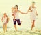 Family of four running on sandy beach on sunny weather