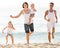 Family of four running on sandy beach on sunny weather