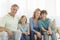 Family Of Four Smiling Together On Sofa