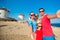 Family of four taking selfie with a stick in front of windmills at popular tourist area on Mykonos island, Greece