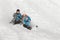 A family of four with the twins slide down a snow hill in winter in the Park