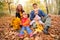 Family of four with yellow leaves sits in wood