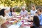 Family and friends serving lunch at a table in the garden