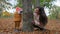 Family games, young woman and little baby boy playing hide and seek beside tree in autumn park