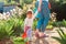 Family gardening. Cute toddler girl rolls a toy cart filled with lettuce while holding on to her mother& x27;s hand