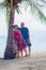 Family, generation - happy smiling grandmother, grandfather and little stand near the palm on the beach