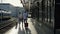 Family with a girl of 5-6 years old is walking along the platform. The passengers are holding suitcases. Back view.