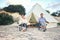 Family glamping outdoor vacation. Mother, father and toddler son sitting near big retro camping tent with cozy interior. Luxury